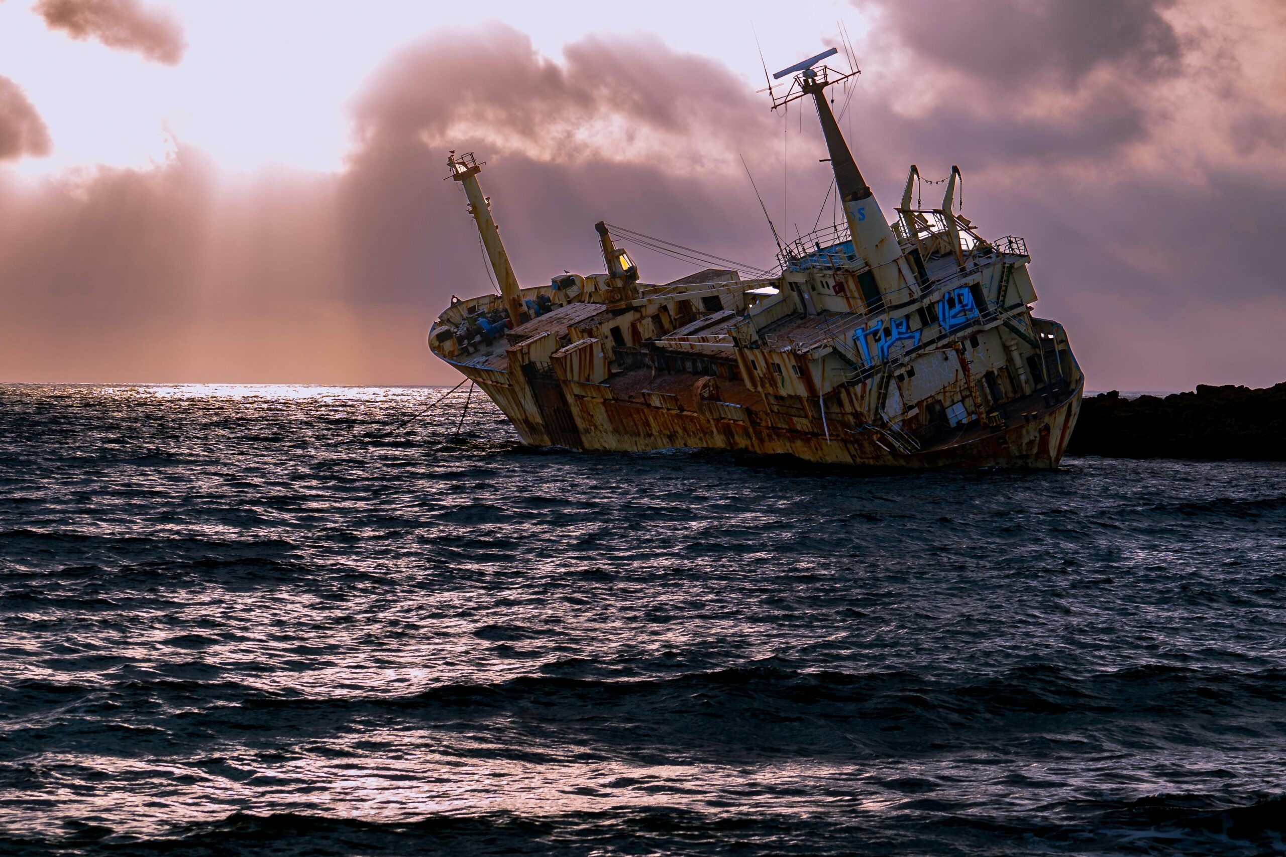 Abandoned shipwreck on a rocky shore at sunset in Cyprus