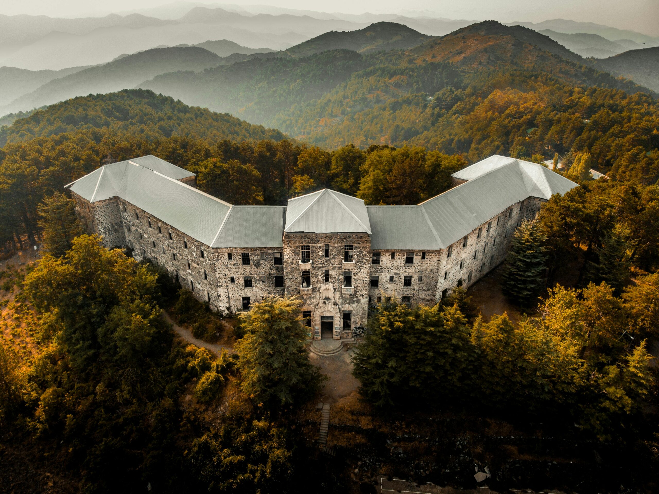 Abandoned Berengaria Hotel surrounded by forested mountains in Cyprus