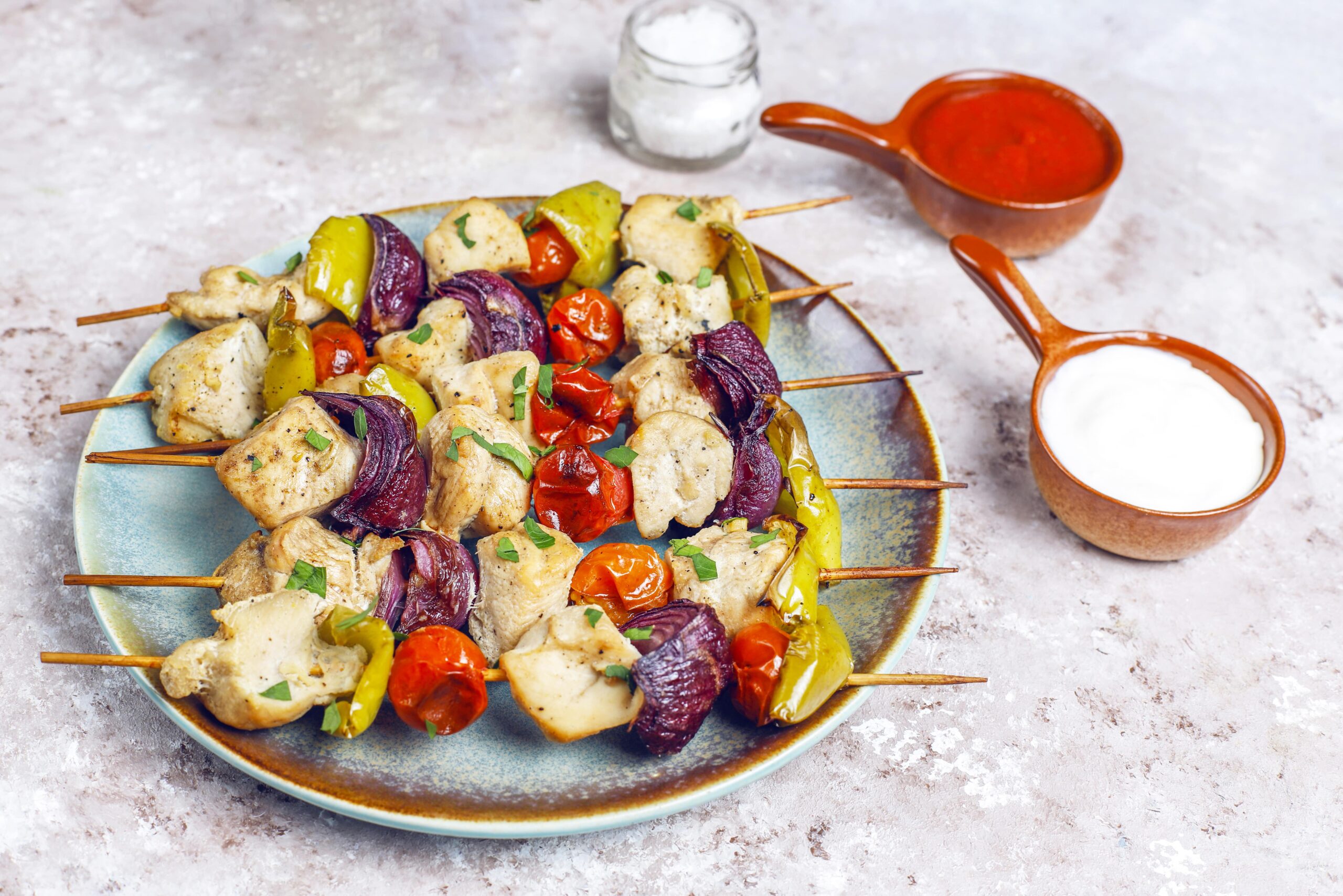 Grilled chicken souvlaki skewers with vegetables served with yogurt and red pepper sauce