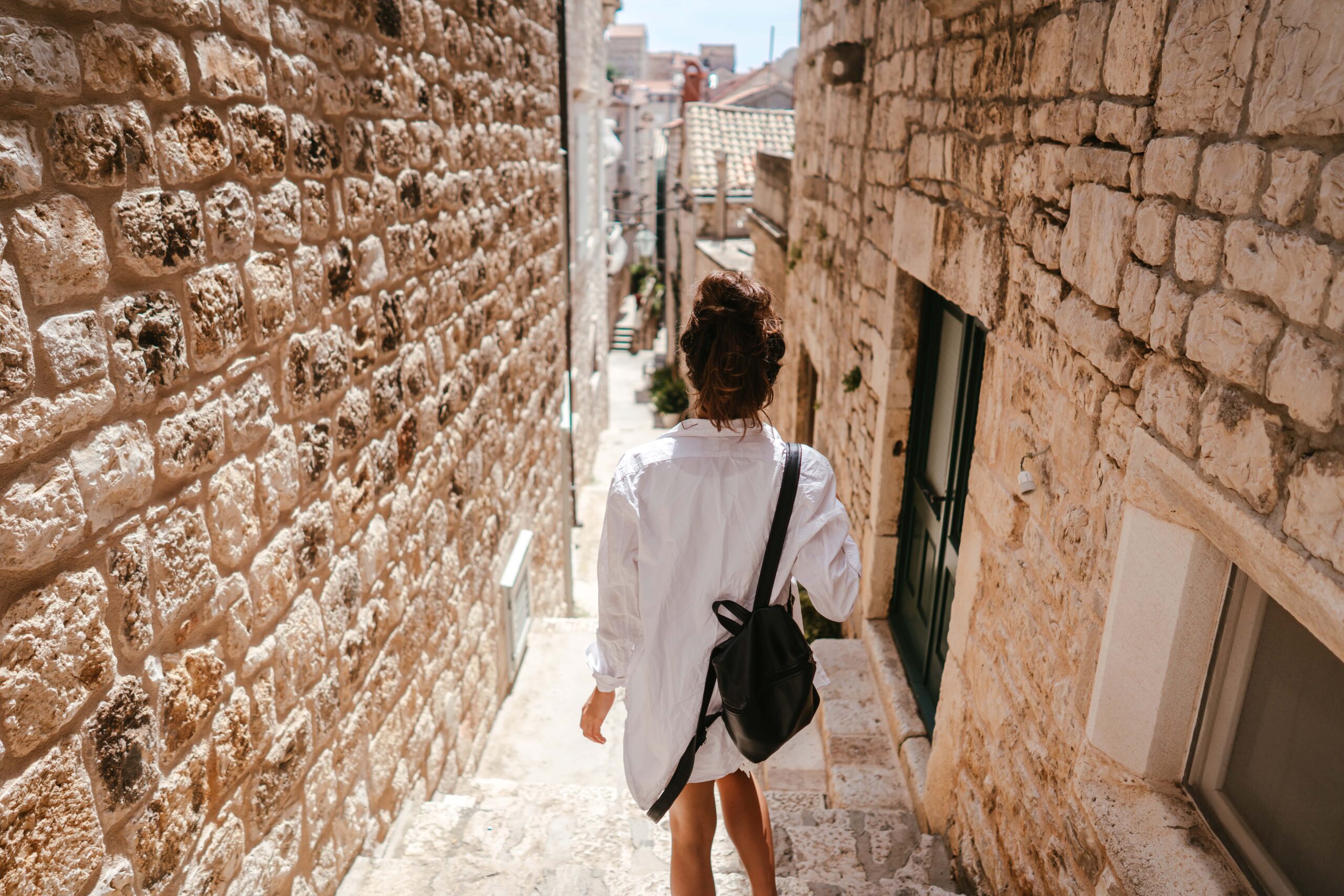 Woman walking down a narrow stone street in a historic Cypriot village