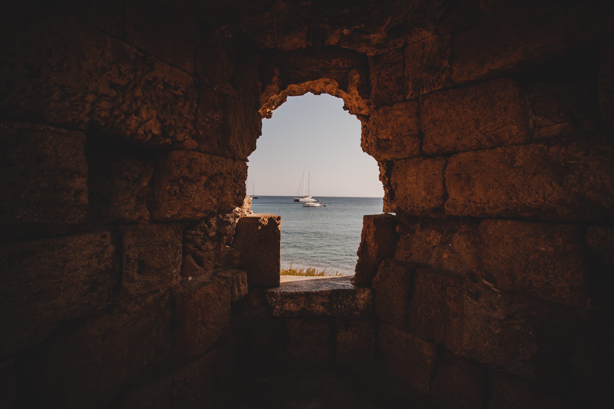 View of sailboats on the sea through an ancient stone archway in Cyprus