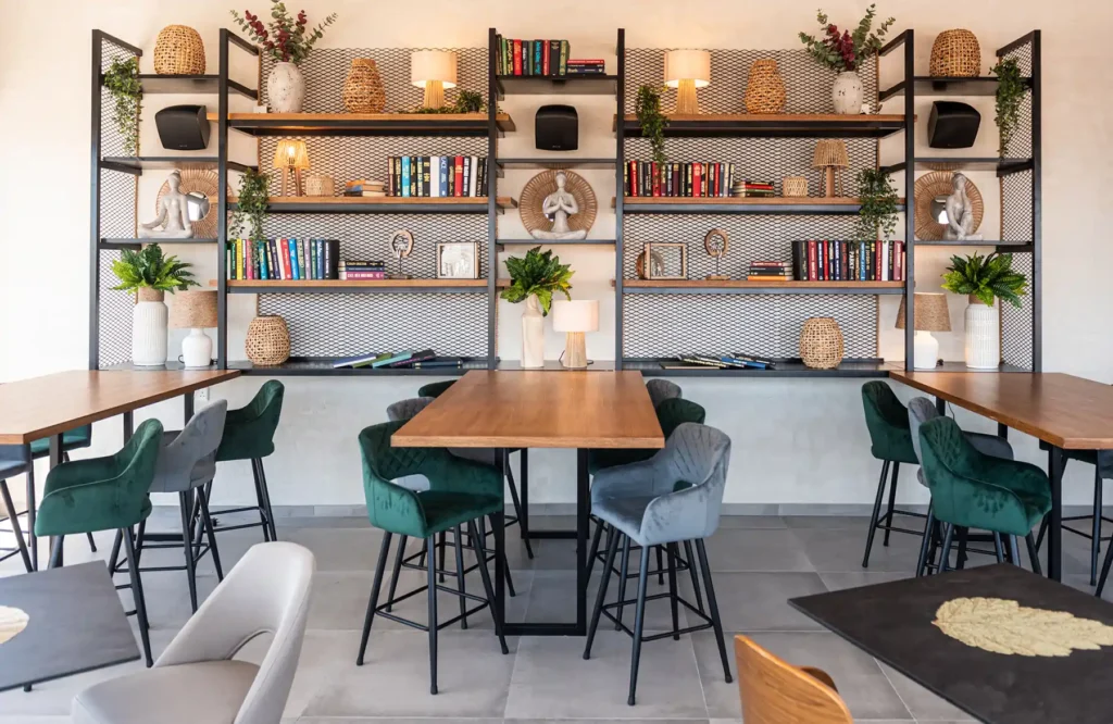 Wooden tables and velvet chairs at Memories Rooftop with bookshelf decor